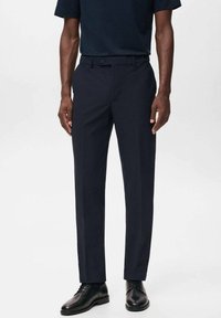 Pantalones de vestir navy con corte slim, frontales lisos y dos bolsillos laterales. La tela tiene una textura suave, combinados con zapatos negros de cordones.