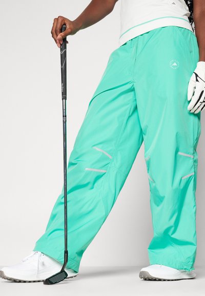 Spodnie golfowe w jasnym odcieniu turkusowym, wykonane z lekkiego materiału. Posiadają kieszenie zapinane na zamek i odblaskowe akcenty. Łączone z białym obuwiem.