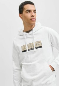 Witte hoodie met een trekkoord, met een opvallend beige en zwart logo op de borst. Zachte stof, kangoeroezak en geribbelde manchetten.