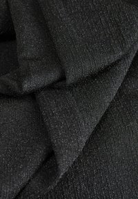 Tessuto nero con una superficie texturizzata, caratterizzato da sottili fili metallici che creano un effetto luccicante. Liscio, morbido e flessibile.