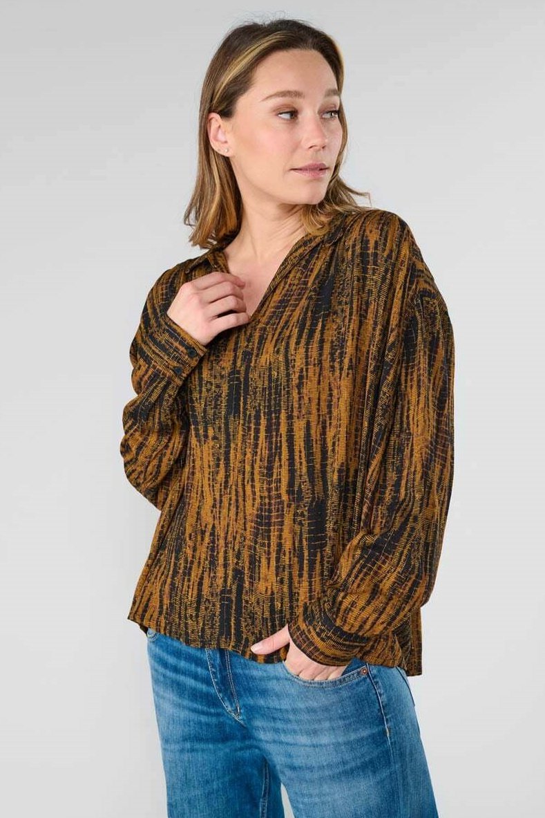 Langsleeve, V-hals top in zwart en bruin met een textuur van abstracte patronen. Zachte stof met een losse pasvorm, gecombineerd met blauwe spijkerbroeken.