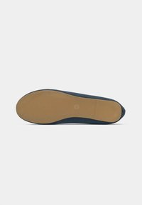 Parte inferiore della scarpa in blu navy con una superficie testurizzata e una suola in gomma color beige. Punta arrotondata e branding minimo visibile sulla suola.