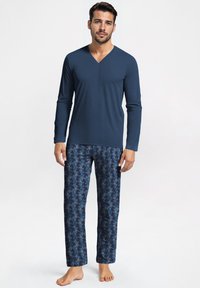 Mannen pyjamapak met een donkerblauwe V-hals lange mouw top en losse lange broeken in donkerdere blauwtinten met een bladpatroon.