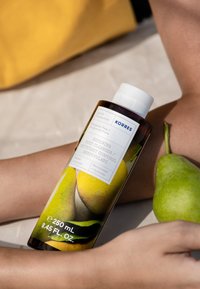 Bottiglia di Korres Renewing Body Cleanser, 250 mL. Vetro marrone con grafiche di pere gialle e verdi, etichetta bianca con testo blu, tappo bianco.