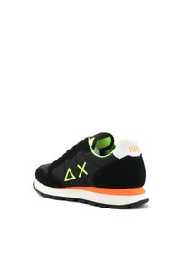 Scarpa sportiva nera con una tomaia in suede e mesh. Presenta foderature verdi, accenti arancioni sulla suola intermedia e un tallone bianco con stampa "1968".