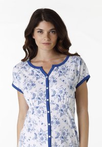 Abito bianco a fantasia floreale con bordi blu e maniche corte, dotato di bottoni sul davanti e vita aderente. Tessuto morbido.