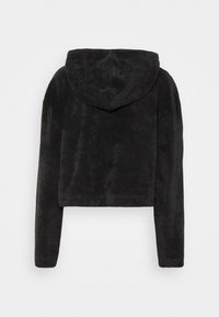 Zwarte cropped hoodie met fijne, pluizige stof en lange mouwen, gezien van achteren tegen een eenvoudige lichte achtergrond.
