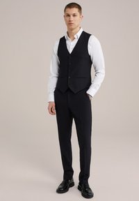 Vesta formală neagră cu cămașă albă, croială ajustată, cinci butoane, două buzunare frontale, asortată cu pantaloni negri și mocasini.