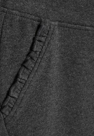 Grå bomullstyg med en texturerad vävd detalj längs fickans söm, vilket skapar en subtil dimension och visuell intresse.