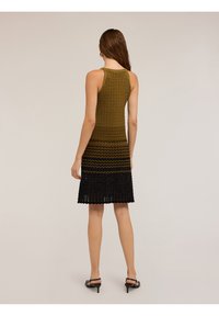 Pletené šaty se zvlněným vzorem, s přechodem od olivově zelené po černou. Bez rukávů, s těsným korzetem a rozšířenou sukní.