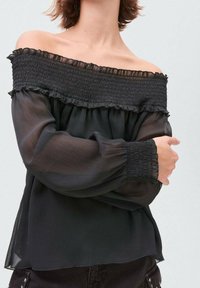 Svart off-the-shoulder-topp med smockad halsringning och volangkant. Genomskinliga långärmar med smockade ärmslut och lös passform. Texturerad tyg.