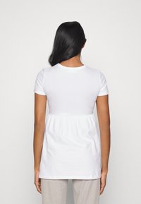 Top bianco a maniche corte con scollatura rotonda, caratterizzato da una vita arricciata, tessuto di cotone morbido e un taglio rilassato che scende sotto i fianchi.