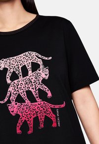 Three pink to red gradient leopard silhouettes stacked vertically on black shirt, with "Marc Cain Sports" text near bottom right.