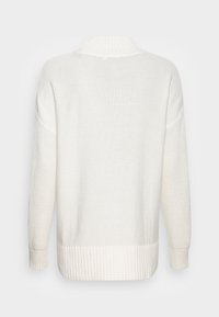 Pull blanc en maille avec col, poignets et ourlet côtelés, montrant des manches texturées et un dos sur un fond uni.