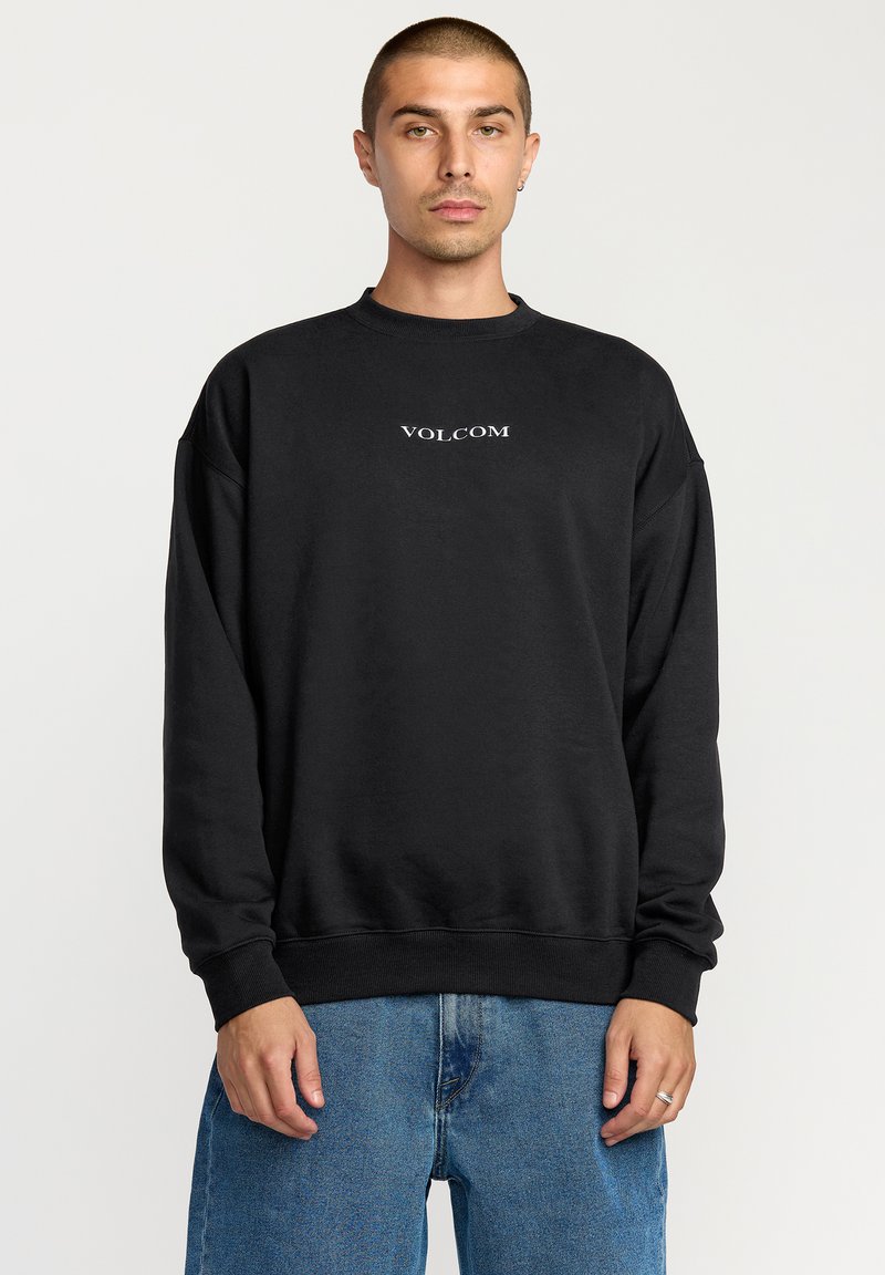 Black sweatshirt with a crew neckline, oversized fit, ribbed cuffs, and a small white "VOLCOM" logo centered on the chest.