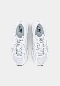Vita sportskor med en ovandel av nätmaterial, rund tå och snörningsdesign. Strukturerade detaljer och logotyp på innersulan synliga.