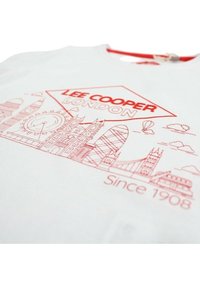 T-shirt en coton blanc avec un dessin graphique rouge représentant des monuments londoniens, dont Big Ben, le Gherkin et le Tower Bridge. Le texte indique "Lee Cooper London Since 1908".