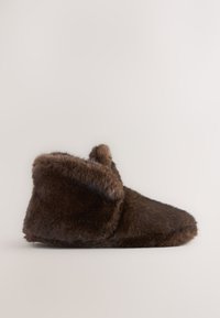 Chausson en fausse fourrure marron avec un bout arrondi et une tige haute, doté d'une doublure intérieure douce et d'une texture moelleuse.