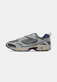 Gray athletic shoe with mesh and synthetic upper, beige sole, dark accents, and branding on the side. Features a textured design and laces.