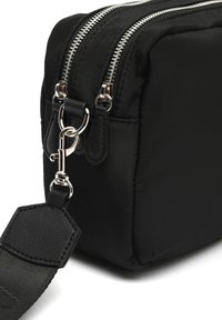 Borsa nera in nylon con due cerniere argentate, dettagli in pelle texture e una tracolla staccabile. Forma rettangolare con un aspetto morbido.