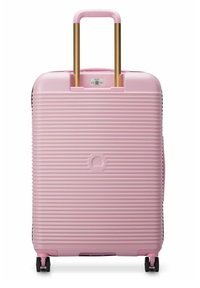 Valigia rigida rosa con design a coste, manico telescopico dorato e quattro ruote nere per la mobilità. Dotata di una maniglia superiore per il trasporto.