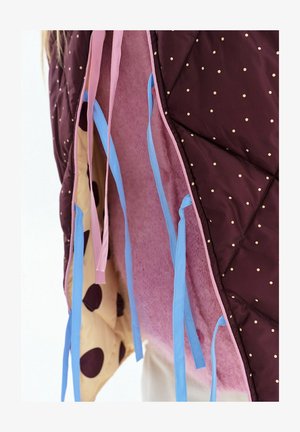 Doskonale pikowana tkanina ze złotymi groszkami, różowa podszewka, beżowa tkanina z dużymi brązowymi plamami oraz niebieskie i różowe paski do zawieszania lub wiązania.