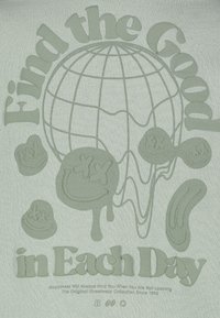 Lichtgroen oversized T-shirt met verhoogd grafisch ontwerp van een globe, lachende gezichten en de tekst "Vind het Goede in Elke Dag".