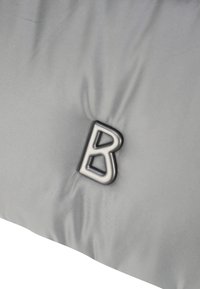 Šedý polstrovaný materiál se zvýšeným černým logem "B", s hladkým povrchem a mírným leskem. Povrch vykazuje jemné vrásky.