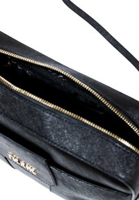 Borsa nera con superficie texturizzata e chiusura con cerniera superiore. Presenta hardware dorato e una tasca esterna. Design semplice e funzionale.