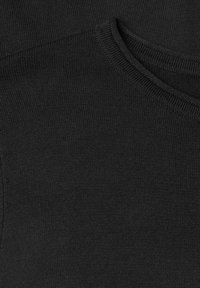 Gros plan sur un tissu en maille noire pliée montrant une texture fine et un bord côtelé au niveau de l'encolure d’un pull ou vêtement.