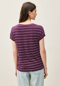 Lilla kortærmet skjorte med lys vandrette striber, rund halsudskæring og en afslappet pasform, parret med lyse denimjeans.