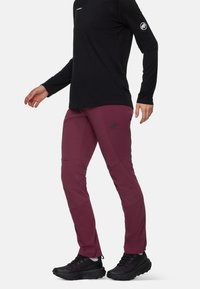 Bordeauxkleurige wandelbroek met een aansluitend ontwerp, gemaakt van synthetisch materiaal. Kenmerken zijn onder andere zijnaad, logo op de heup en versterkte knieën.