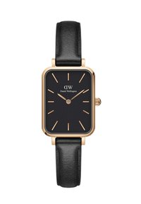 Kandiline musta värvi kell kuldsete aksessuaaridega, nahkrihm ja lihtsad tunni markerid. Kellal on must nägu, millel on brändi nimi "Daniel Wellington."