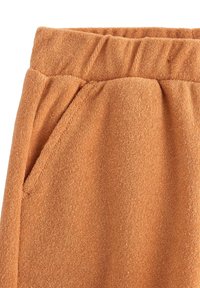 Håndklæde-tekstur shorts i en lys orange farve, med en elastisk talje, tekstur der minder om frotté, og sidelommer.