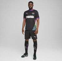 Conjunto de fútbol negro de mangas cortas, con un diseño lateral en gradiente multicolor, acentos morados y estampados de logotipos. Incluye pantalones cortos y calcetas.