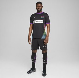 Melna futbola forma ar īsām piedurknēm, kas iekļauj daudzkrāsainu gradienta sānu dizainu, purpura akcentus un logotipa apdrukas. Iekļauts šorti un zeķes.