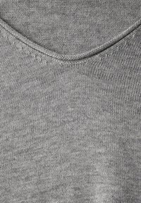 Grau gestrickter Stoff mit einer glatten Textur, der über einen runden Halsausschnitt und dezente Nähedetails entlang der Kanten verfügt.