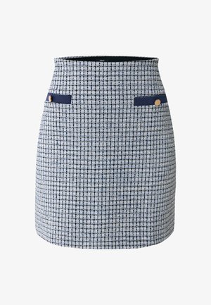 Marineblauer und weißer Tweed-Rock mit kurzem Schnitt, zwei seitlichen Taschen mit marineblauen Akzenten und goldenen Knopfdetails. Strukturierter Stoffüberzug.