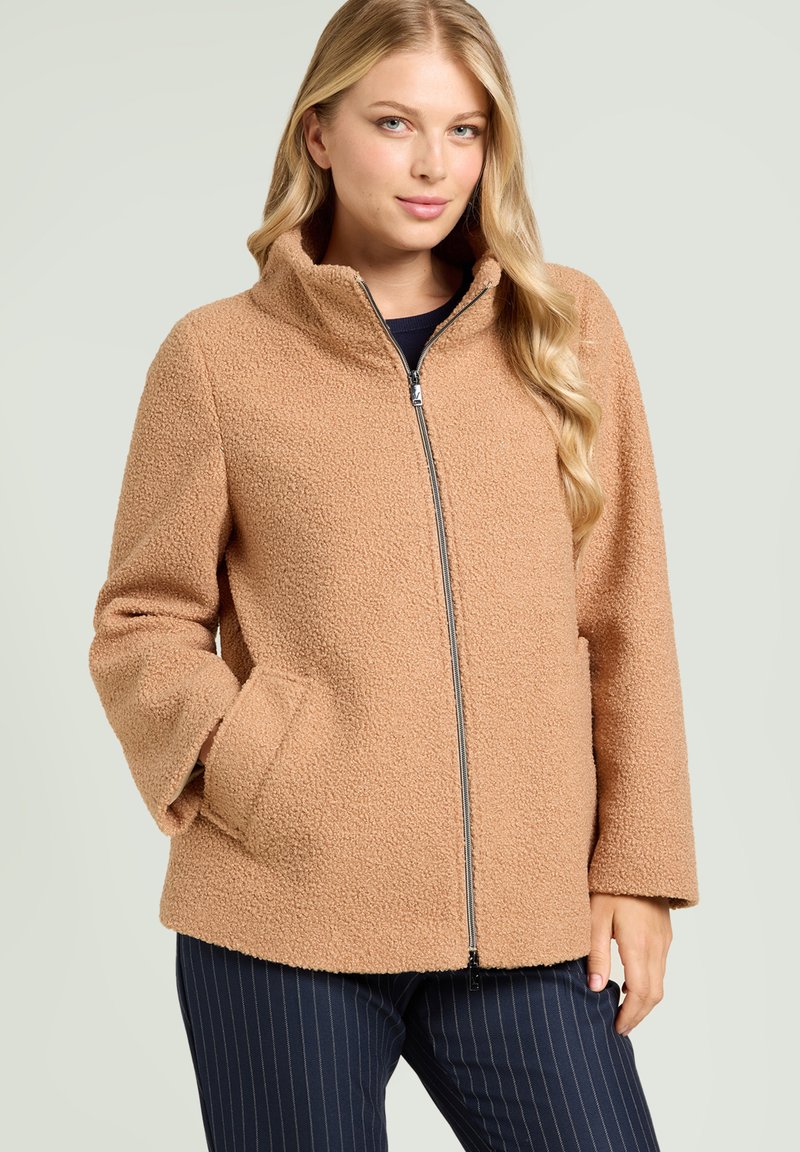 Giacca in pile marrone con colletto alto, zip frontale e tasche laterali. Materiale morbido e dalla texture con vestibilità ampia e taglio dritto.