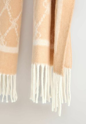 Persikinės spalvos vilnos šalikas su geometriniu raštu, su baltais kutais ant galų. Minkšta tekstūra ir šiltas, jaukus išvaizda.