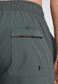 Pantaloni corti grigi con cintura elastica, dotati di una tasca posteriore con pattina, etichetta del marchio visibile e un design con cuciture rinforzate.