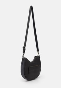 Svart läder axelväska med en böjd form, har en dragkedjeficka på framsidan och en justerbar rem för bekvämlighet.