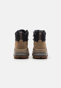 Braune und schwarze Wanderschuhe mit Obermaterial aus Wildleder und Textil, Gummisohle und einem ausgeprägten Schnürsystem mit verstärktem Absatz für zusätzliche Unterstützung.