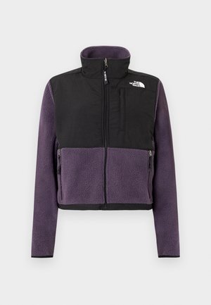 Chaqueta de forro polar con la mitad inferior en morado y la mitad superior en negro, cierre frontal con cremallera, cuello alto y dos bolsillos laterales con cierre de cremallera.