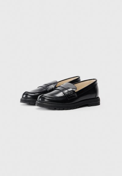 Sorte skinnloafers med rund tå, med flat såle og et dekorativt belte over vristen. Glatt tekstur og minimal detaljer.