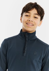 Pullover mezza zip di colore blu navy, realizzato in tessuto traspirante, con finitura testurizzata, logo nero e colletto alto per il calore.