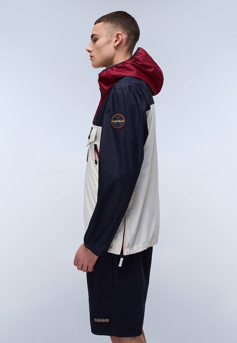 Chaqueta resistente al agua con un diseño bicolor en azul marino y crema, con capucha color burdeos, bolsillos con cremallera y parche del logo en la manga.