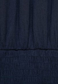 Temno modra tkanina z gubano teksturo, ki vključuje nabranje in gladke prehode na šivih. Klasična zasnova z bogato barvo.