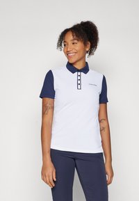 Πόλο μπλούζα Calvin Klein με άσπρο σώμα και ναυτικά μπλε μανίκια, με γιακά, κουμπιά και κομψή εφαρμογή.