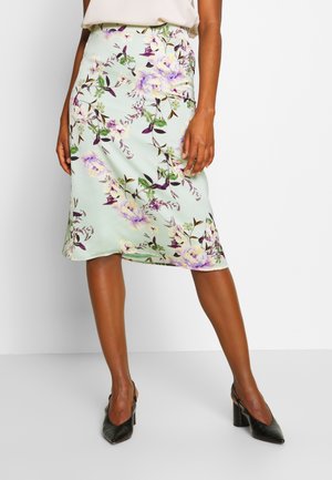 Jupe florale en satin vert menthe avec des fleurs violettes et jaunes, de longueur genou, légèrement évasée, avec une texture lisse et une taille.